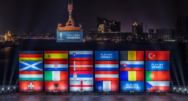 JvM Sports und Segmenta inszenieren Gruppenauslosung der UEFA Euro 2024 - 25 Container, 12 x 70 Tonnen schwere Reach Stacker (Containerstapler) und 70 Hafenmitarbeiter waren Teil der spektakulären gemeinsamen Aktion von JvM Sports und Segmenta Communications, bei der die Gruppenauslosung – Final Draw – Foto: JvM